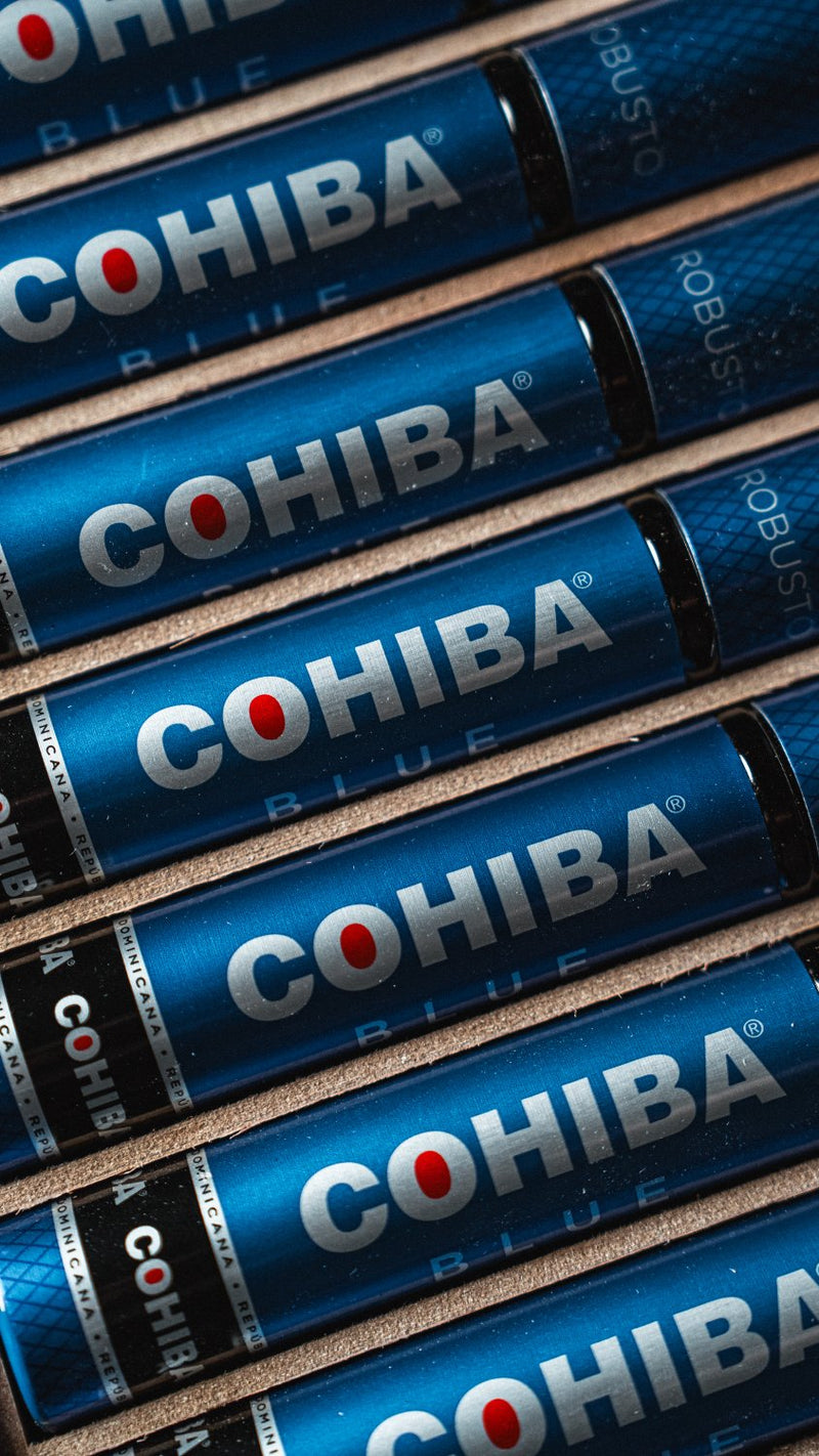 A close-up diagonal arrangement of several blue Cohiba cigar rolling machines with the brand name 'COHIBA' printed in white and a small red dot logo.